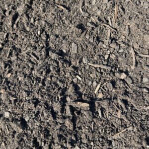 Close-up of dry soil with small pebbles and wood chips scattered on the surface