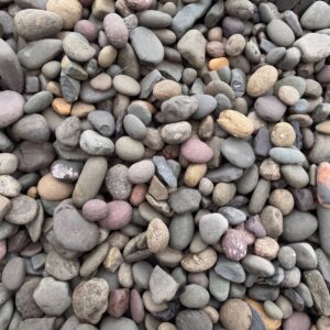 Close-up of a mix of smooth, rounded river pebbles in gray, tan, pink, and blue hues.