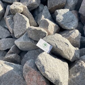 Close-up of gray rocks with a white card featuring a green tree logo and 'Pine Straw Place' branding.